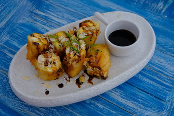 Fried banana with melted chocolate. Served on a white ceramic plate. banana fritters. 