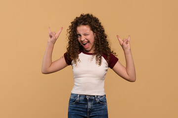 Young girl flashing rock hand signs with enthusiastic expression