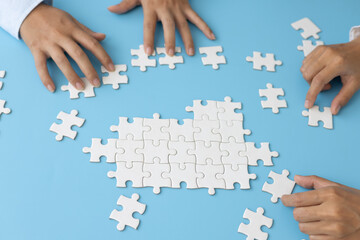 Business team holding parts of jigsaw puzzle trying to find solution to problem together.  Concept...