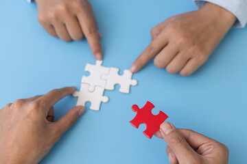 Business team holding parts of jigsaw puzzle trying to find solution to problem together.  Concept...