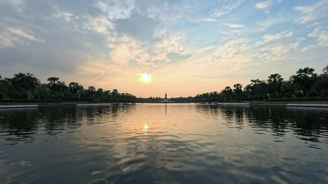 Time Lapse of sunset view of walking Buddha statue in the background of sunset in Phutthamonthon, Nakhon Pathom Thailand.