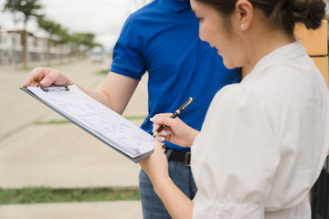 Home Delivery Confirmation: Woman signing delivery documents with a courier. Focus on the...