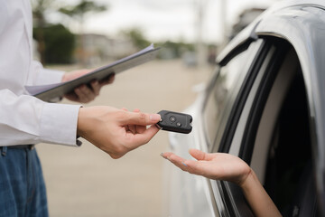 Car Key Handover:  A close-up shot of a car key being exchanged between a salesperson and a...