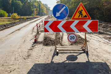 A construction site on a country road with a set of road signs directing vehicles. Temporary road...