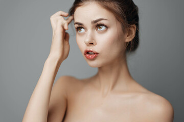 Serious young woman posing with hands on head and looking at the camera