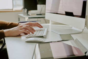 Medium closeup of unrecognizable male hands typing on modern desktop computer keyboard at workplace...