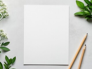 A blank sheet of paper surrounded by greenery and pencils. Ideal for showcasing creativity and minimalism in design projects.
