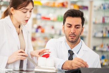 Pharmacists counting drug pills arranging assortment working in drug shelves counter