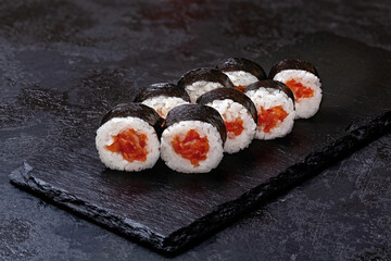 Japanese sushi, rolls with salmon in nori seaweed on a black background