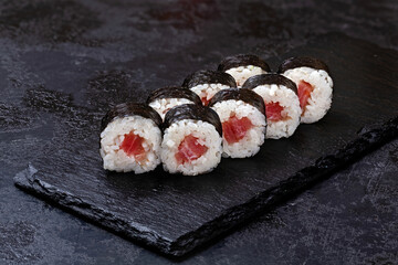 Japanese sushi, rolls with tuna in nori seaweed on black background
