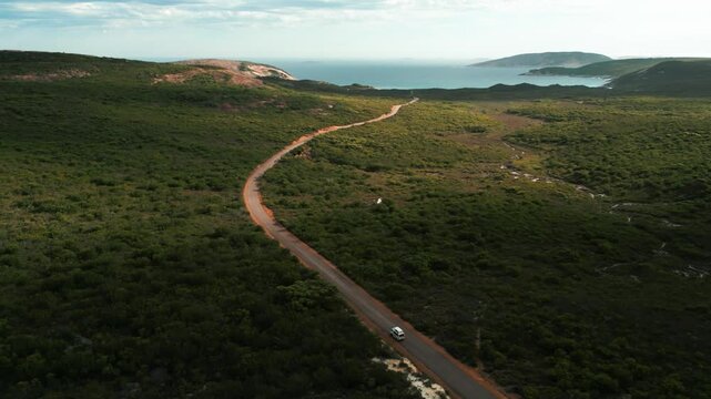 aerial shot over hellfire road in Cape Legrand National Park following a van driving on a dirt road to hellfire bay on a cloudy day in Western Australia