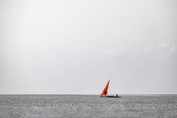 Monochrome Ocean Photograph with a Small Red Sailing Boat
