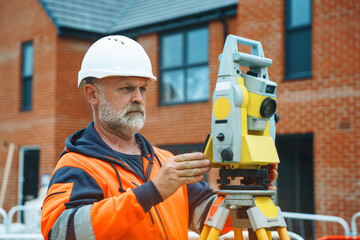 Experienced surveyor meticulously aligning equipment at a construction site during daylight hours