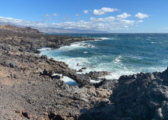 Rocky beach volcanic landscape in Tenerife, Canary  islands in a sunny windy day, the ocean waves...