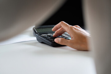 Focused Businesswoman Using Calculator for Financial Analysis in Modern Office Setting