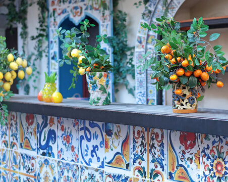 Branch with lemons, tangerines in ceramic vase on table. Traditional pattern, Sicily, Italy. Fruit and decor. 