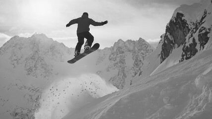 A snowboarder performs an impressive jump in the snowy mountains during winter