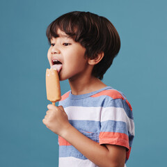 Japanese boy, bite and ice cream in studio background with sweet snack or sucker for fun. Male...