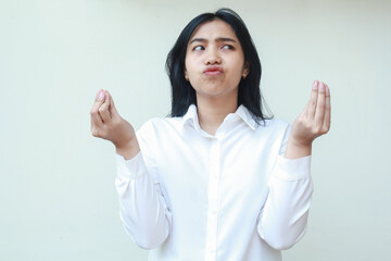 portrait of thoughtful asian young business woman manager looking aside wondering curious with curled up fingers raised hands wearing white formal suit, standing