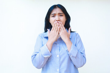 shocked asian woman covering her mouth wide open wearing striped shirt isolated on white background
