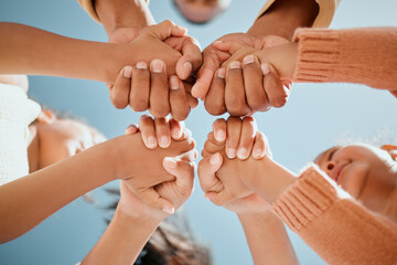 Children, holding hands and unity below with blue sky for community, care or trust in support. Low...