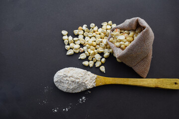 Corn flour pile in wooden spoon with black and green, Bowl with corn starch, A close-up pile of organic Corn Seeds (Zea mays) or Makka, isolated on a white background. Top view, in bag