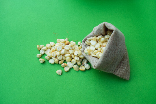 Dry corn seeds bag. Prepare to make corn flour. Native agriculture in countryside concept, A close-up pile of organic Corn Seeds (Zea mays) or Makka, isolated on a green  background. Top view, jawar
