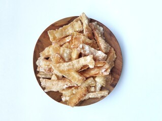 Kripik singkong or cassava chips on wooden plate isolated on white background. Indonesian traditional foods famous in Java 