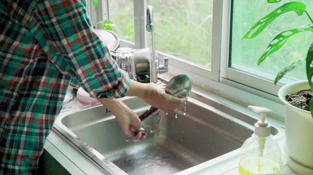 Time Lapse video woman wearing scott shirt work home be cleaning , wash the dishes. Morning in the sink in a happy home kitchen