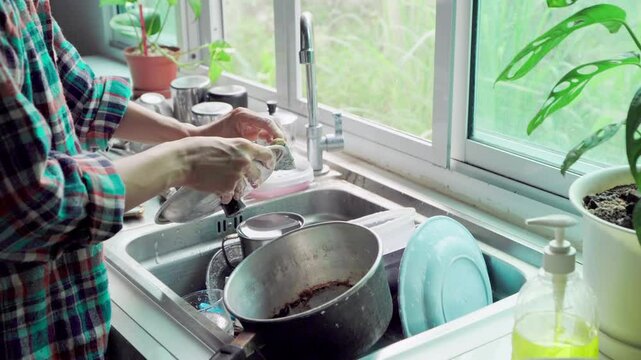 Time Lapse video woman wearing scott shirt work home be cleaning , wash the dishes. Morning in the sink in a happy home kitchen