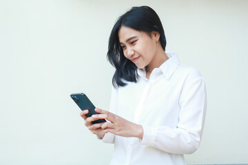 Naklejka premium beauty grateful asian business woman satisfied online shopping via smartphone, browsing social media read good news, try new apps, wearing white formal suit shirt, standing isolated