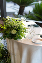 This stunning floral centerpiece features vibrant greenery and fragrant blooms, elegantly arranged on a table, perfect for weddings, anniversaries, parties, and other joyful celebrations