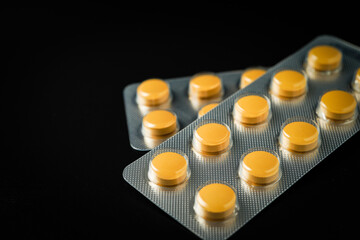 Pills Medicine tablet Brown Yellow in blister pack on a black background