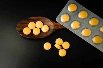 Pills Medicine tablet capsules blister pack in wooden spoon on a black background