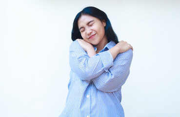 Fototapeta premium happy asian woman hug her self with tenderness feel comfortable wearing striped shirt isolated on white background, self love concept