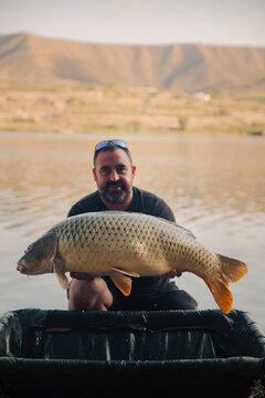 Fisherman showing the carp he just caught in a swamp