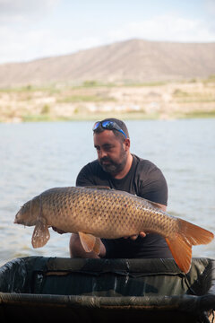 Fisherman showing the carp he just caught in a swamp