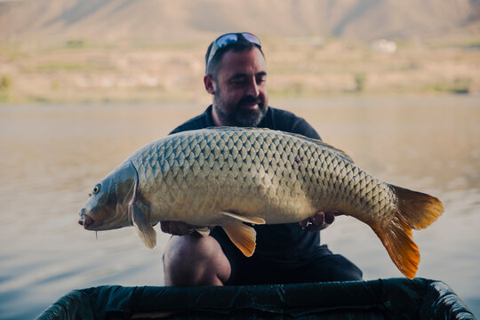 Fisherman showing the carp he just caught in a swamp
