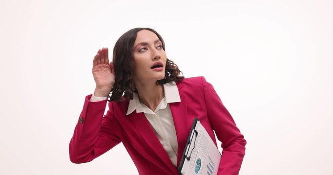 Businesswoman in vibrant red suit holds clipboard listening with attention on white background. Brunette woman shows astonishment with gossip