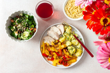 Boiled potatoes, roasted vegetables, and lean chicken breast come together with a fresh salad of tomatoes and cucumbers with seeds, accompanied by a light raspberry compote