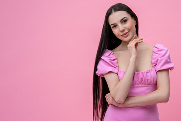 Pretty young long-haired woman in pink dress looking dreamy