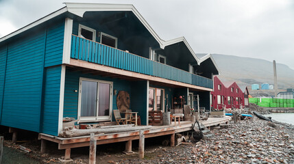 Colorful wooden buildings line Longyearbyen\'s waterfront on an overcast day