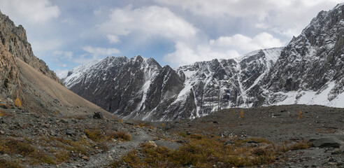 High resolution panoramic image of mountain landscape. Stone ground, thin mountain pathway,  steep slopes, gray rocky vertical mountains in Altai nature of golden autumn.