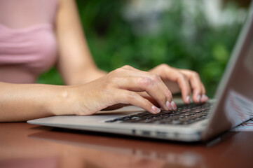 Naklejka premium A close-up of a woman working on her laptop, typing on the laptop keyboard, working remotely.