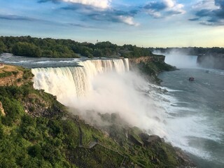 Fototapeta premium Scenic view of Niagara Falls with mist and boat.