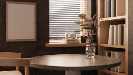 A round dark stone marble table by the window and a bookshelf in a cozy contemporary room.