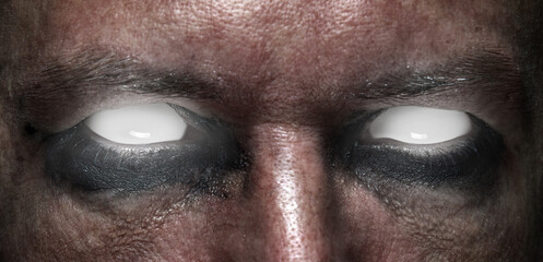 Chilling close-up of face with pitch-black eye makeup and glowing white eyes. Ghost inside. Concept...