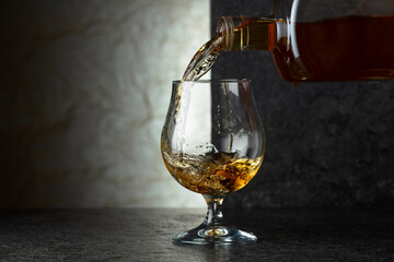 Pouring brandy from a bottle into a glass.