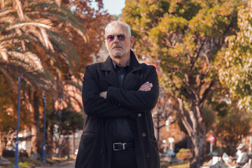 Mature man with coat with arms crossed in autumn