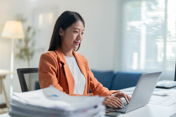 Businesswoman is working from her home office. She is smiling and focused on her work, surrounded...